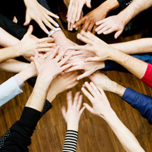 Image of a team placing their hands in a circle