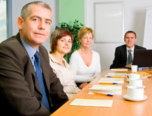 Image of co-workers sitting at a boardroom table.